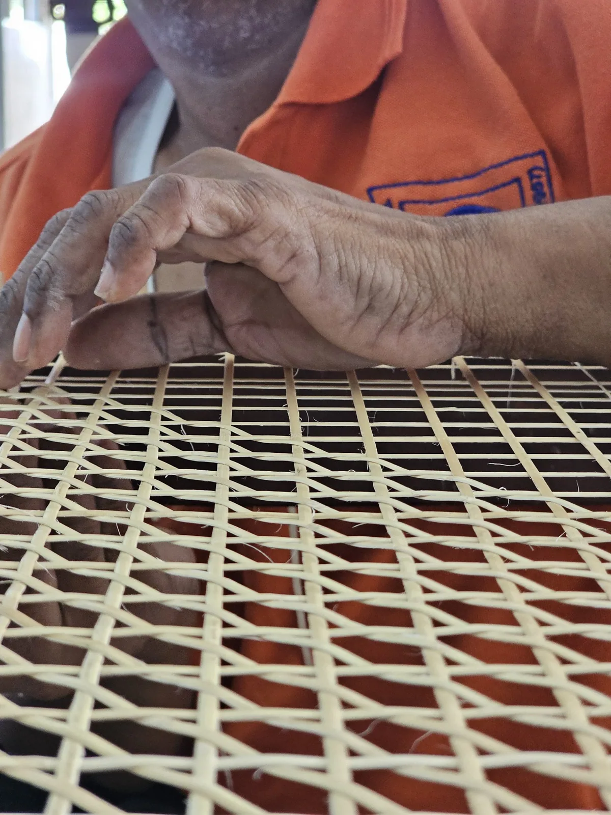 Close-up of artisan’s hands weaving a cane pattern